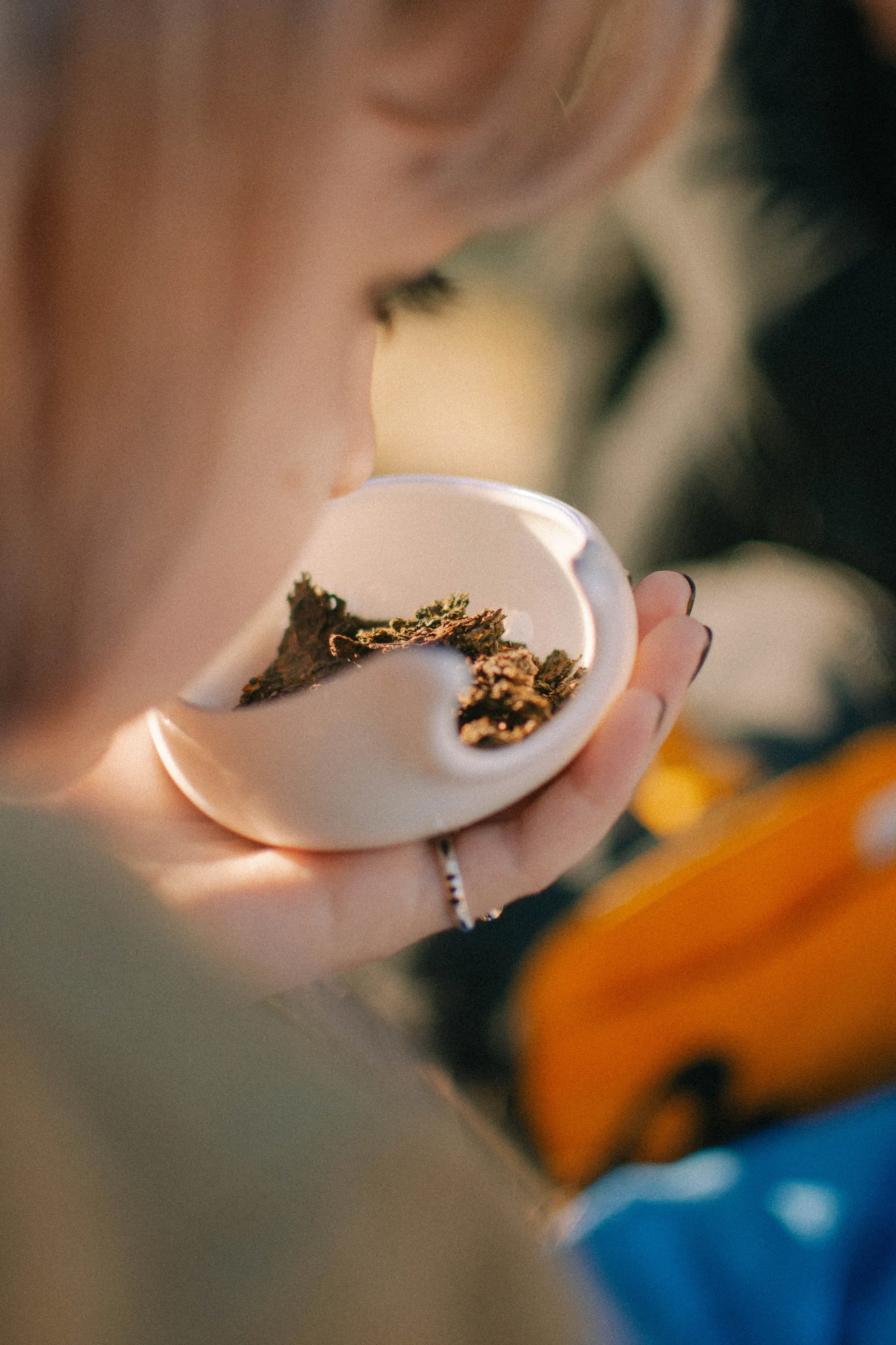 Hands holding a small white bowl in warm light.